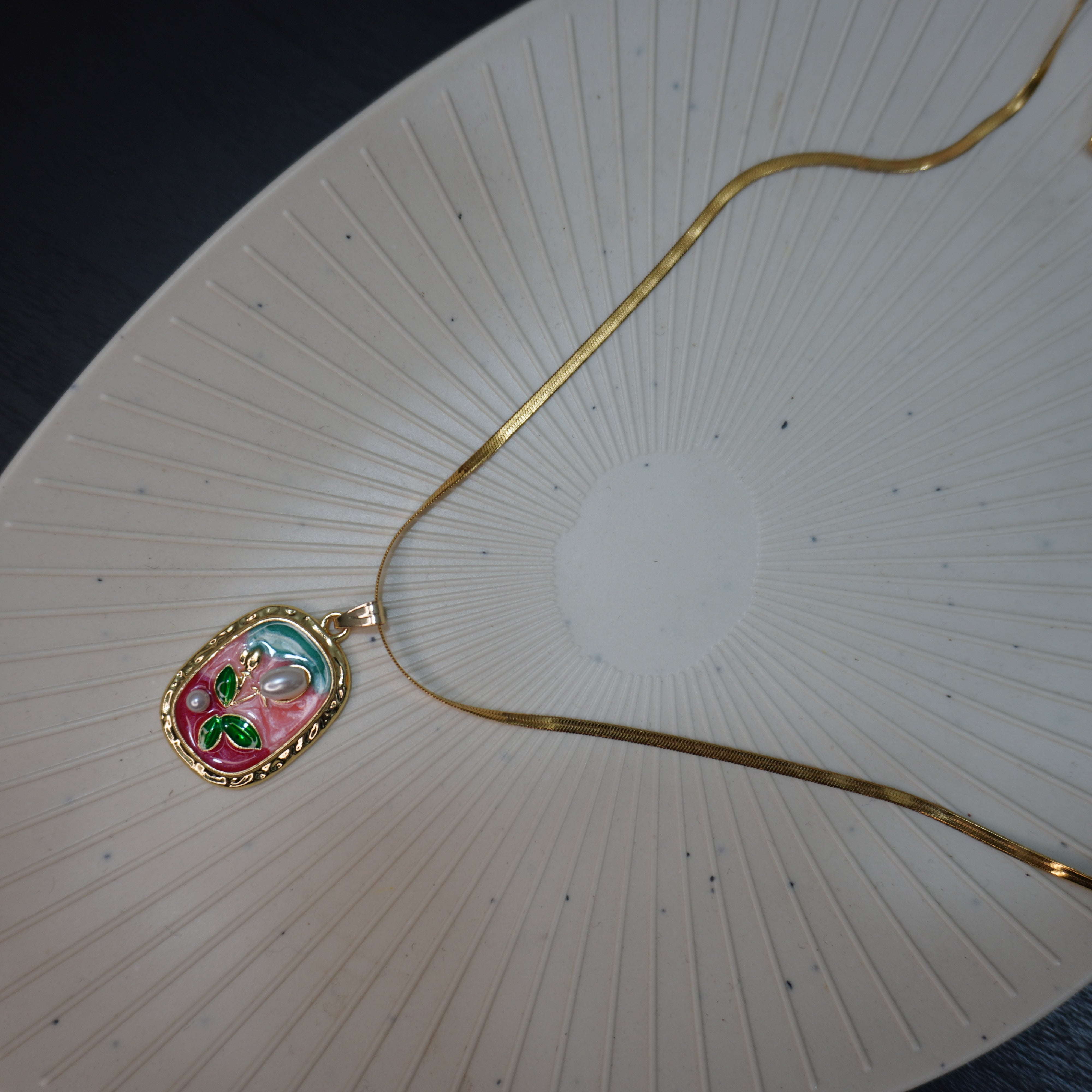 Gold necklace with a decorative pendant on a textured white surface